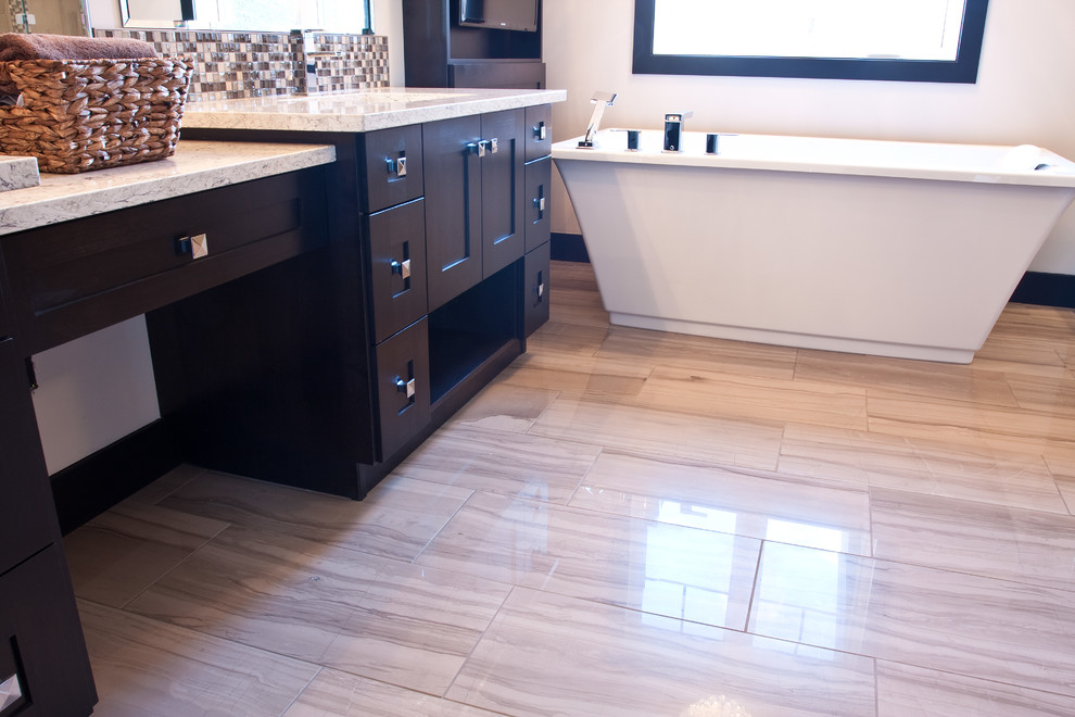 This is an example of a large contemporary ensuite bathroom in Calgary with a submerged sink, black cabinets, granite worktops, a freestanding bath, a walk-in shower, multi-coloured tiles, mosaic tiles, beige walls and porcelain flooring.