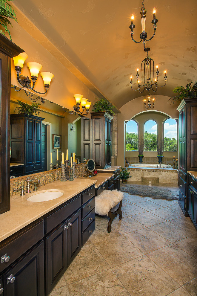 Exempel på ett stort medelhavsstil en-suite badrum, med luckor med upphöjd panel, skåp i mörkt trä, ett platsbyggt badkar, en hörndusch, beige kakel, stenkakel, beige väggar, klinkergolv i porslin, ett undermonterad handfat, marmorbänkskiva, beiget golv och dusch med gångjärnsdörr
