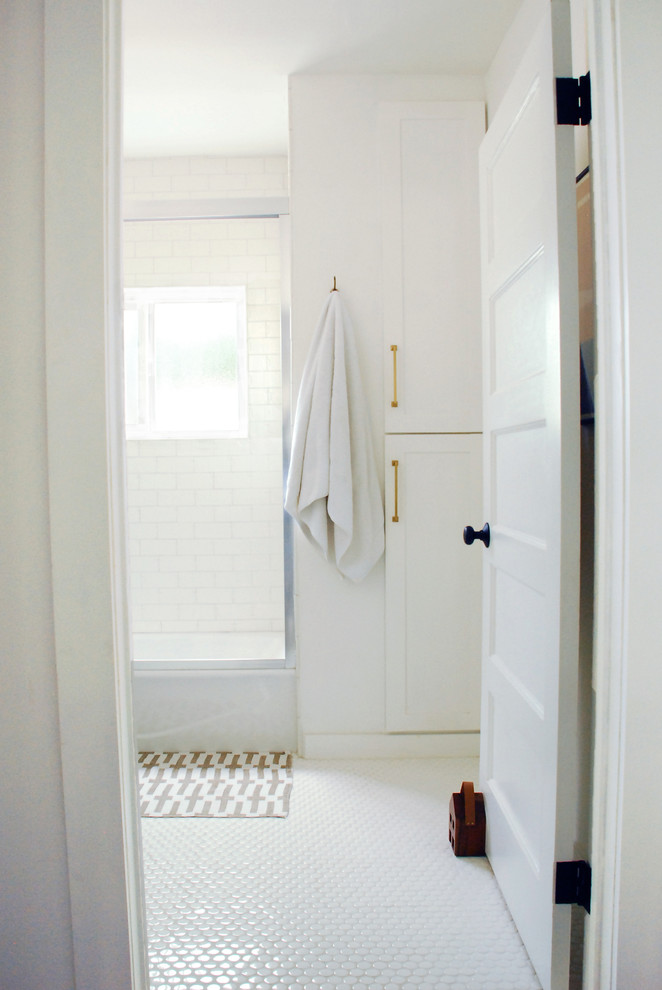 Aménagement d'une petite salle de bain classique avec des portes de placard bleues, une baignoire en alcôve, un combiné douche/baignoire, un carrelage blanc, des carreaux de céramique, un mur blanc, un sol en carrelage de céramique, un lavabo encastré, un plan de toilette en calcaire, un sol blanc et une cabine de douche à porte coulissante.