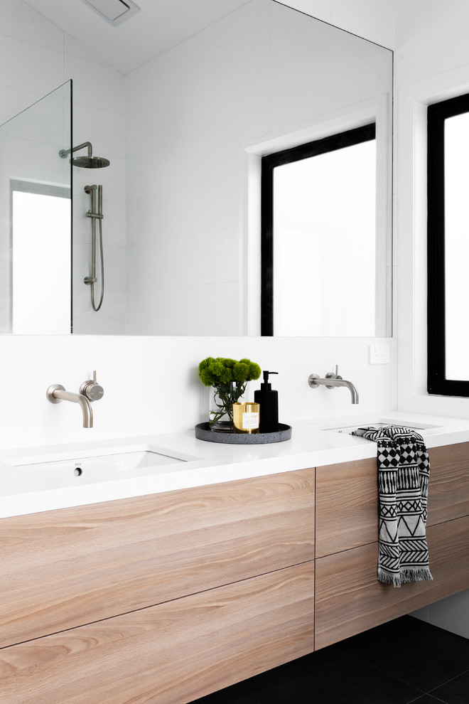 Modernes Badezimmer mit flächenbündigen Schrankfronten, hellen Holzschränken, weißer Wandfarbe, Unterbauwaschbecken, schwarzem Boden und weißer Waschtischplatte in Melbourne