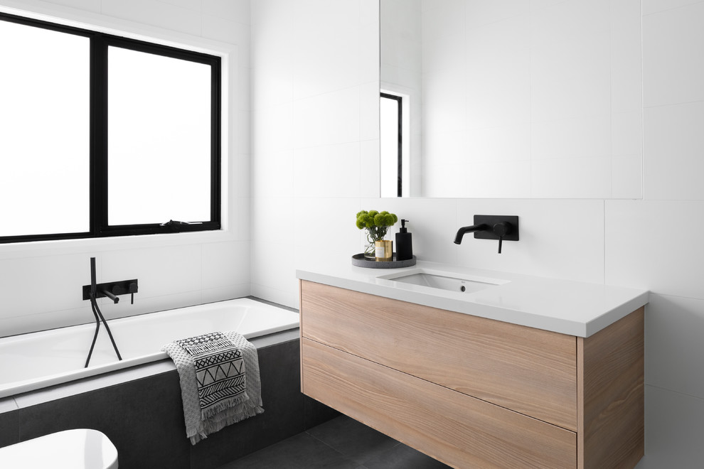 Modernes Badezimmer mit flächenbündigen Schrankfronten, hellen Holzschränken, weißen Fliesen, Unterbauwaschbecken, grauem Boden und weißer Waschtischplatte in Melbourne