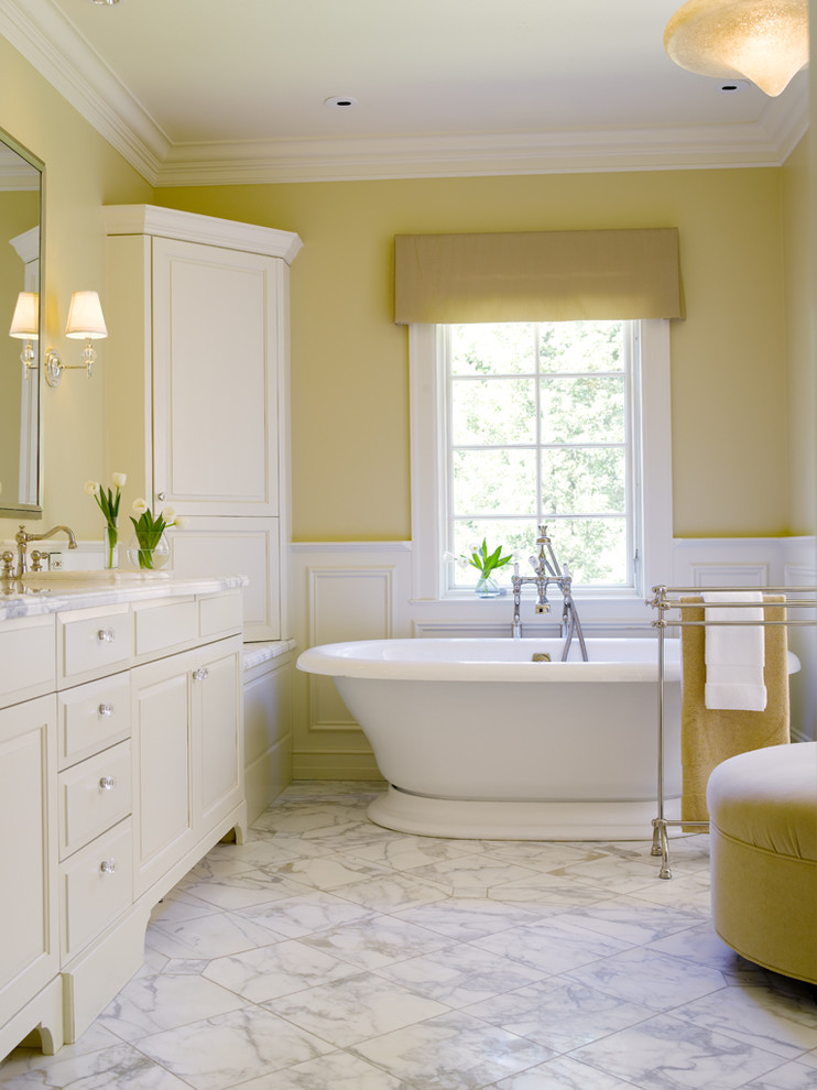 Diseño de cuarto de baño tradicional con bañera exenta, paredes amarillas, suelo de mármol y suelo blanco