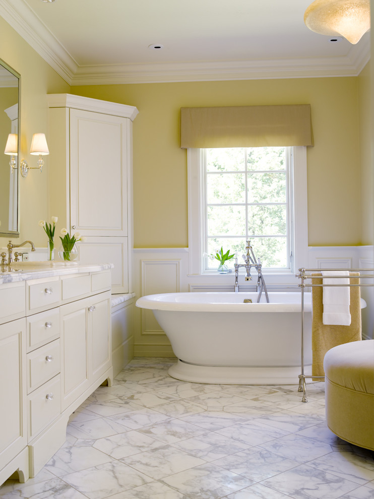 Example of a classic marble floor and white floor freestanding bathtub design in Seattle with yellow walls