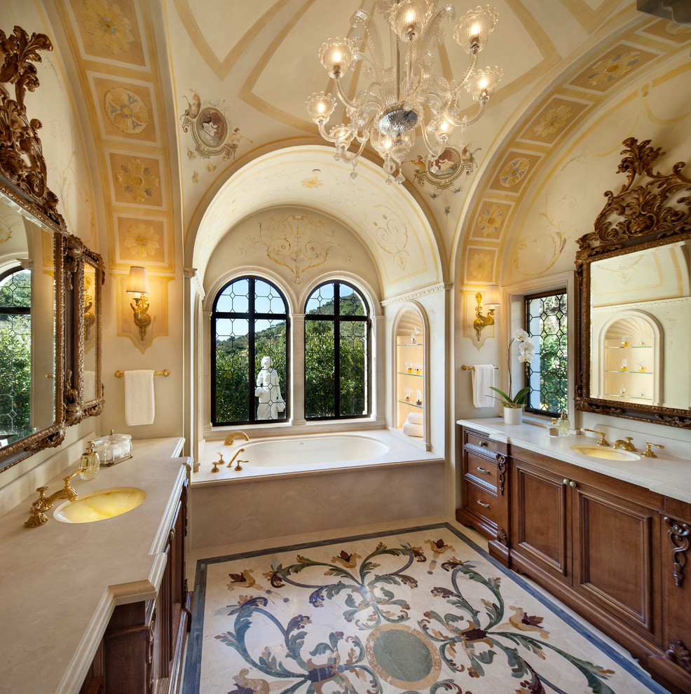 サンタバーバラにあるラグジュアリーな地中海スタイルのおしゃれな浴室 (アンダーカウンター洗面器、アルコーブ型浴槽、濃色木目調キャビネット、落し込みパネル扉のキャビネット) の写真