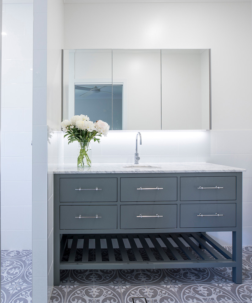 This is an example of a medium sized classic family bathroom in Townsville with blue cabinets, a walk-in shower, white tiles, ceramic tiles, white walls, porcelain flooring, a submerged sink, marble worktops, grey floors, an open shower and white worktops.