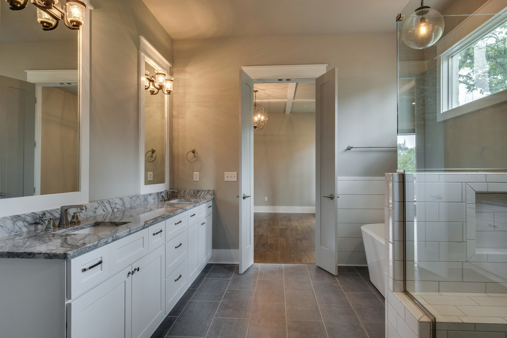 Photo of a large traditional ensuite bathroom in Nashville with shaker cabinets, white cabinets, a freestanding bath, a corner shower, white tiles, metro tiles, grey walls, slate flooring, a submerged sink and a hinged door.