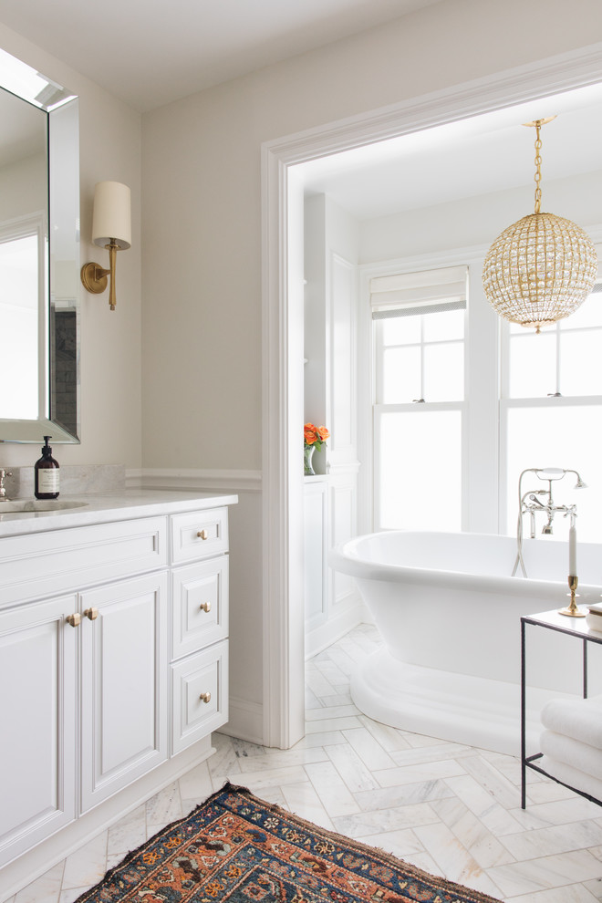 Immagine di una stanza da bagno chic con ante con bugna sagomata, ante bianche, pareti beige, lavabo sottopiano, pavimento bianco e top bianco
