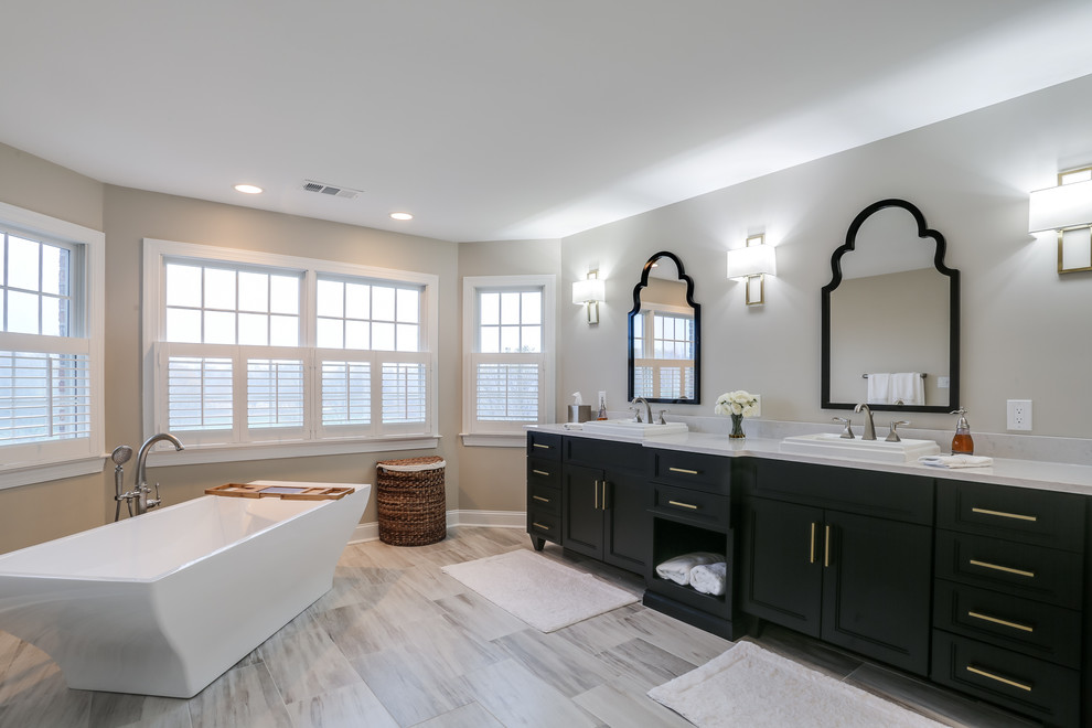 На фото: большая главная ванная комната в классическом стиле с фасадами островного типа, черными фасадами, отдельно стоящей ванной, угловым душем, серыми стенами, накладной раковиной и столешницей из искусственного кварца