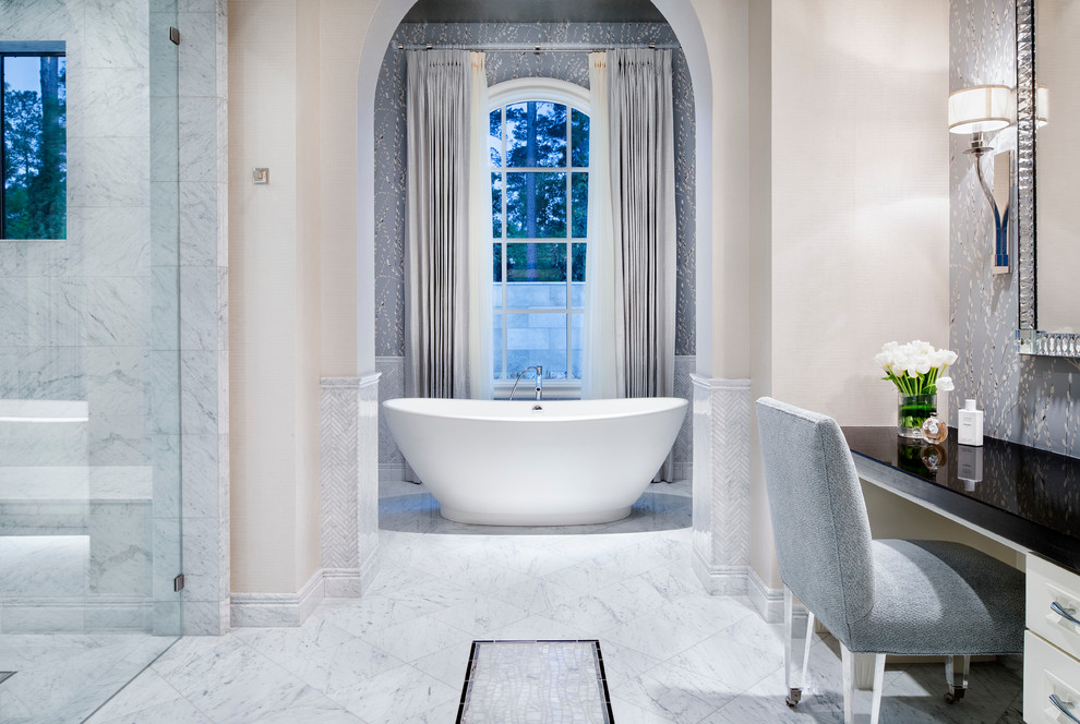 Cette image montre une salle de bain principale traditionnelle avec une baignoire indépendante, un placard à porte plane, des portes de placard blanches, un carrelage gris, un mur multicolore et un sol en marbre.