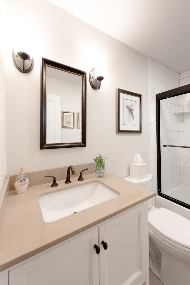 Idéer för att renovera ett mellanstort vintage en-suite badrum, med luckor med infälld panel, vita skåp, ett badkar i en alkov, en dusch/badkar-kombination, en toalettstol med separat cisternkåpa, vit kakel, keramikplattor, beige väggar, klinkergolv i porslin, ett undermonterad handfat och bänkskiva i kvartsit