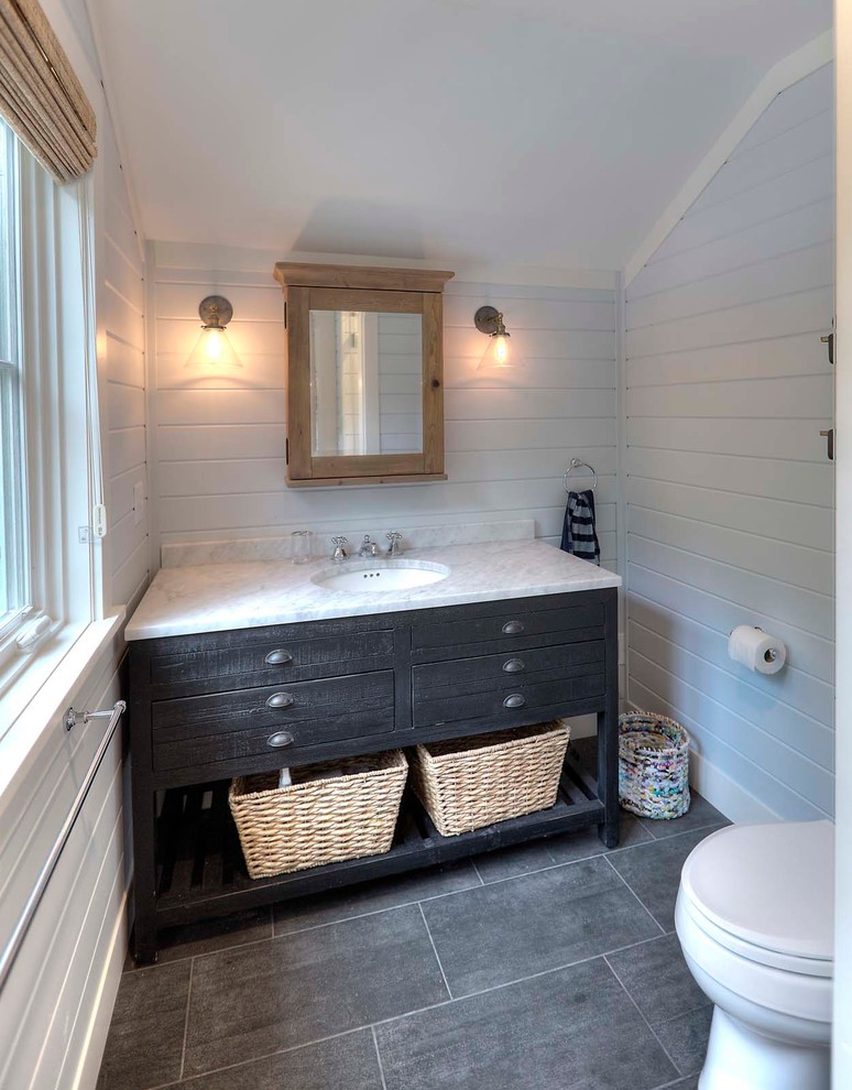 Modelo de cuarto de baño costero de tamaño medio con armarios con paneles lisos, puertas de armario negras, paredes blancas, suelo de pizarra, aseo y ducha, lavabo bajoencimera y encimera de mármol