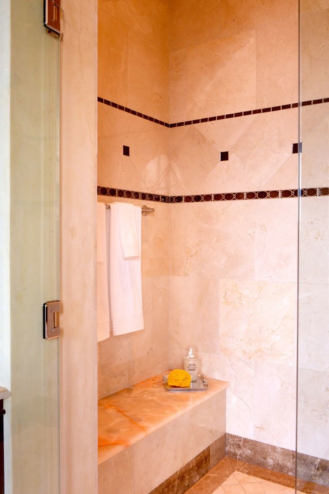 Exempel på ett mycket stort klassiskt en-suite badrum, med ett undermonterad handfat, luckor med upphöjd panel, skåp i mörkt trä, bänkskiva i onyx, ett fristående badkar, en dusch i en alkov, en toalettstol med hel cisternkåpa, beige kakel, stenkakel, beige väggar och marmorgolv