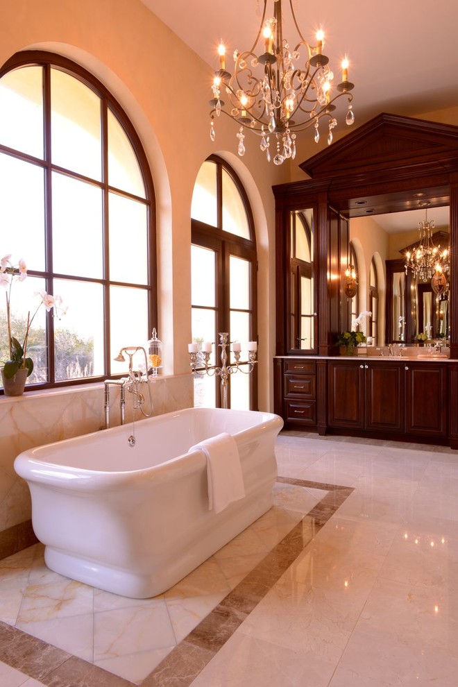 Exemple d'une très grande douche en alcôve principale chic en bois foncé avec un lavabo encastré, un placard avec porte à panneau surélevé, un plan de toilette en onyx, une baignoire indépendante, WC à poser, un carrelage beige, un carrelage de pierre, un mur beige et un sol en marbre.