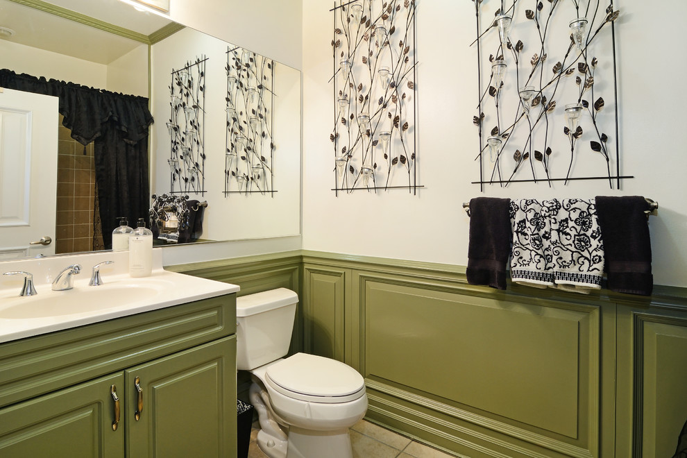Elegant beige tile and ceramic tile bathroom photo in New York with an integrated sink, flat-panel cabinets, green cabinets, solid surface countertops and a two-piece toilet
