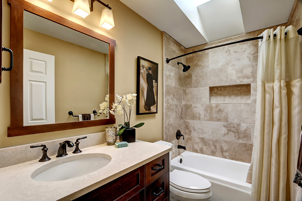 Design ideas for a medium sized traditional family bathroom in Seattle with shaker cabinets, dark wood cabinets, an alcove bath, a shower/bath combination, beige tiles, stone tiles, beige walls, a submerged sink and engineered stone worktops.