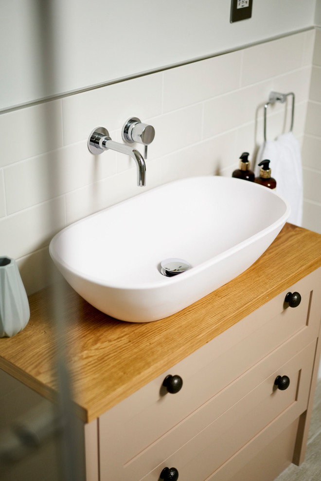 Small classic ensuite bathroom in Sussex with flat-panel cabinets, beige cabinets, a walk-in shower, a one-piece toilet, multi-coloured tiles, ceramic tiles, white walls, ceramic flooring, a trough sink, wooden worktops, beige floors and a sliding door.