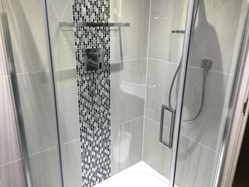 This is an example of a modern bathroom in Essex with black cabinets, a corner shower and grey tiles.