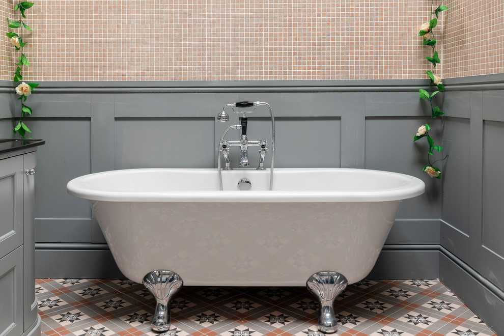 Foto på ett stort vintage svart badrum, med möbel-liknande, grå skåp, ett fristående badkar, rosa kakel, mosaik, grå väggar, klinkergolv i porslin, marmorbänkskiva och flerfärgat golv