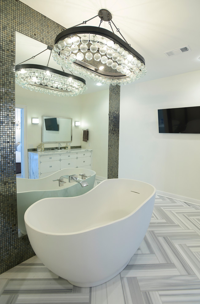 Cette image montre une salle de bain design avec un placard à porte plane, des portes de placard blanches, une baignoire indépendante et un mur blanc.