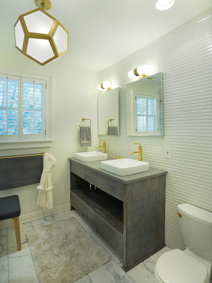 Cette photo montre une salle de bain chic avec une vasque, un placard à porte plane, des portes de placard grises, WC séparés, un carrelage blanc, un mur blanc et un plan de toilette gris.