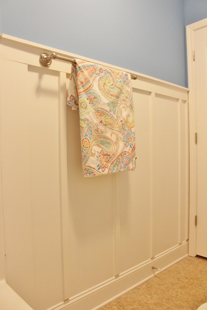 Exemple d'une petite salle de bain craftsman pour enfant avec un placard avec porte à panneau surélevé, des portes de placard blanches, un combiné douche/baignoire, un mur bleu, un sol en vinyl, un lavabo posé et un plan de toilette en stratifié.