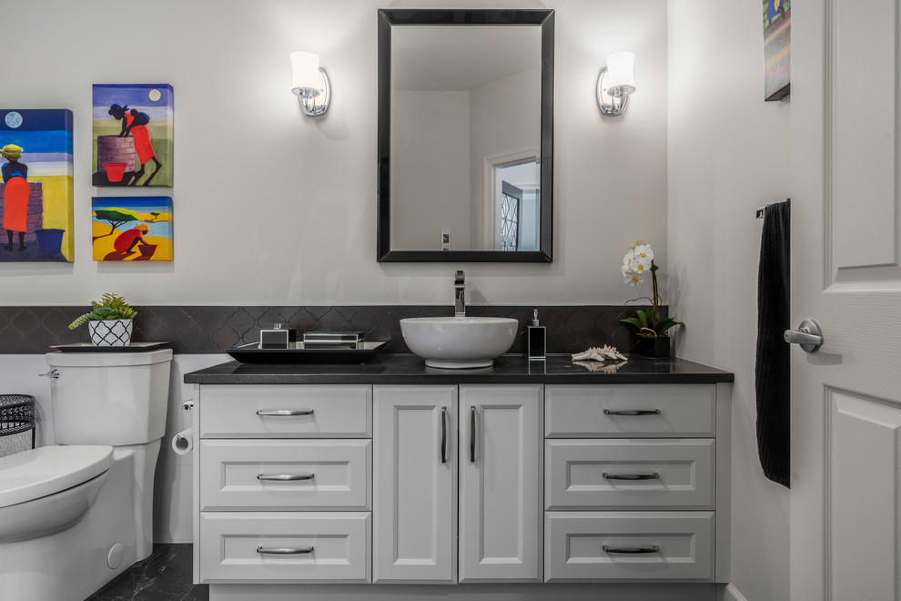 Exemple d'une salle de bain principale chic de taille moyenne avec des portes de placard blanches, WC à poser, un carrelage noir, un mur blanc, un sol en carrelage de céramique, une vasque, un plan de toilette en quartz modifié, un sol noir, un plan de toilette noir, une baignoire indépendante et un placard à porte shaker.