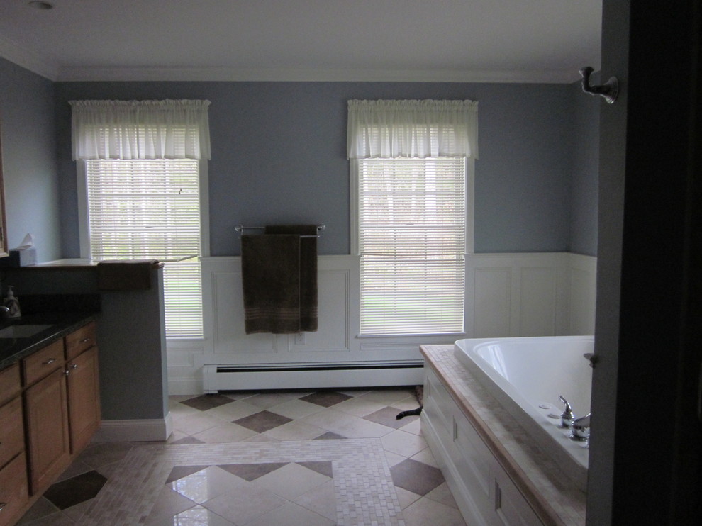 Immagine di una stanza da bagno classica con ante con bugna sagomata, ante in legno scuro, vasca da incasso, pareti blu, pavimento in gres porcellanato, lavabo sottopiano, top in granito e pavimento multicolore