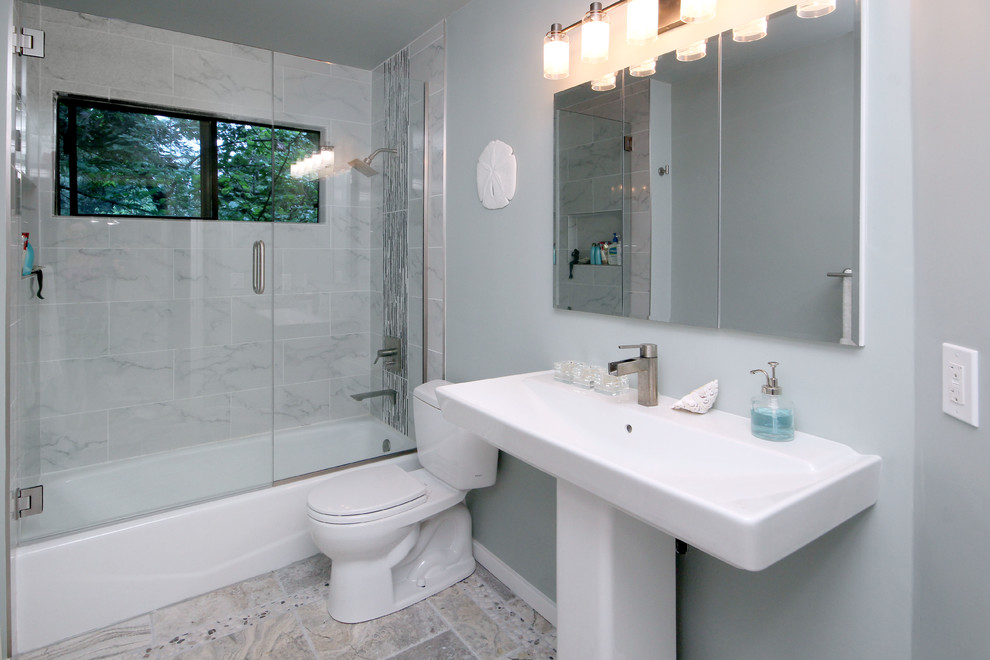 Пример оригинального дизайна: ванная комната среднего размера в стиле модернизм с раковиной с пьедесталом, душем над ванной, раздельным унитазом, серой плиткой, галечной плиткой, синими стенами, полом из керамогранита и душевой кабиной