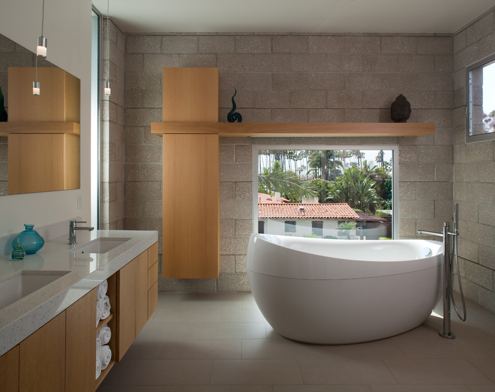 サンディエゴにあるコンテンポラリースタイルのおしゃれな浴室 (アンダーカウンター洗面器、フラットパネル扉のキャビネット、中間色木目調キャビネット、置き型浴槽、グレーのタイル) の写真