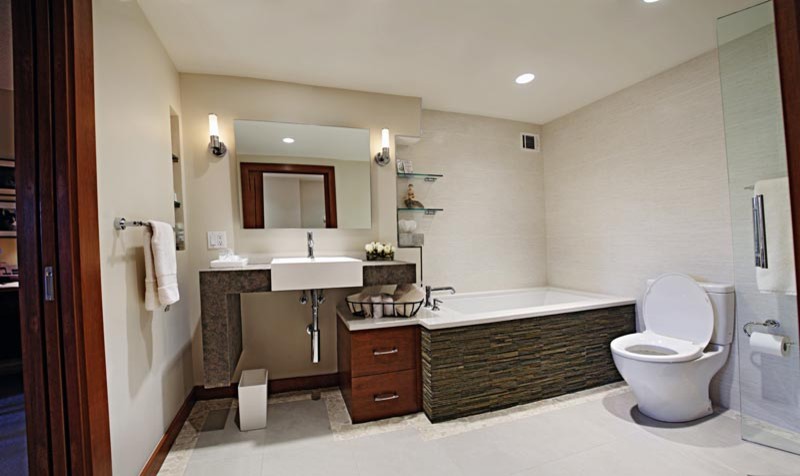 Photo of a medium sized contemporary ensuite bathroom in DC Metro with flat-panel cabinets, medium wood cabinets, a submerged bath, an alcove shower, a one-piece toilet, beige tiles, ceramic tiles, beige walls, ceramic flooring, a wall-mounted sink and concrete worktops.