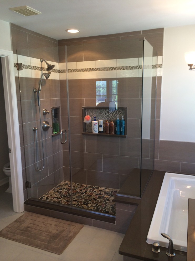 Cette photo montre une grande salle de bain principale moderne avec une vasque, un plan de toilette en quartz, une baignoire posée, une douche ouverte, une plaque de galets et un sol en carrelage de porcelaine.