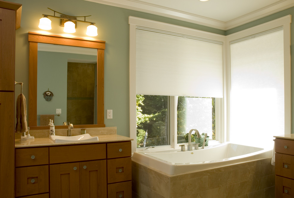 Cette photo montre une grande salle de bain principale moderne en bois brun avec un lavabo posé, un placard à porte shaker, une baignoire d'angle, un mur vert et un carrelage beige.