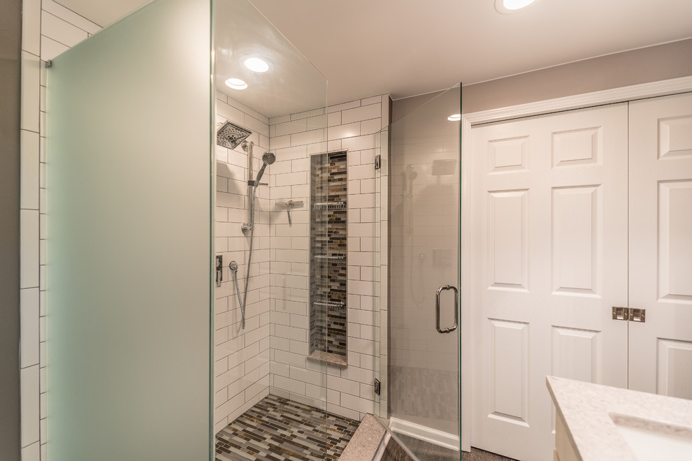 На фото: главная ванная комната среднего размера в современном стиле с плоскими фасадами, серыми фасадами, угловым душем, раздельным унитазом, белой плиткой, плиткой из листового стекла, серыми стенами, полом из винила, врезной раковиной, стеклянной столешницей, разноцветным полом, душем с распашными дверями и серой столешницей с