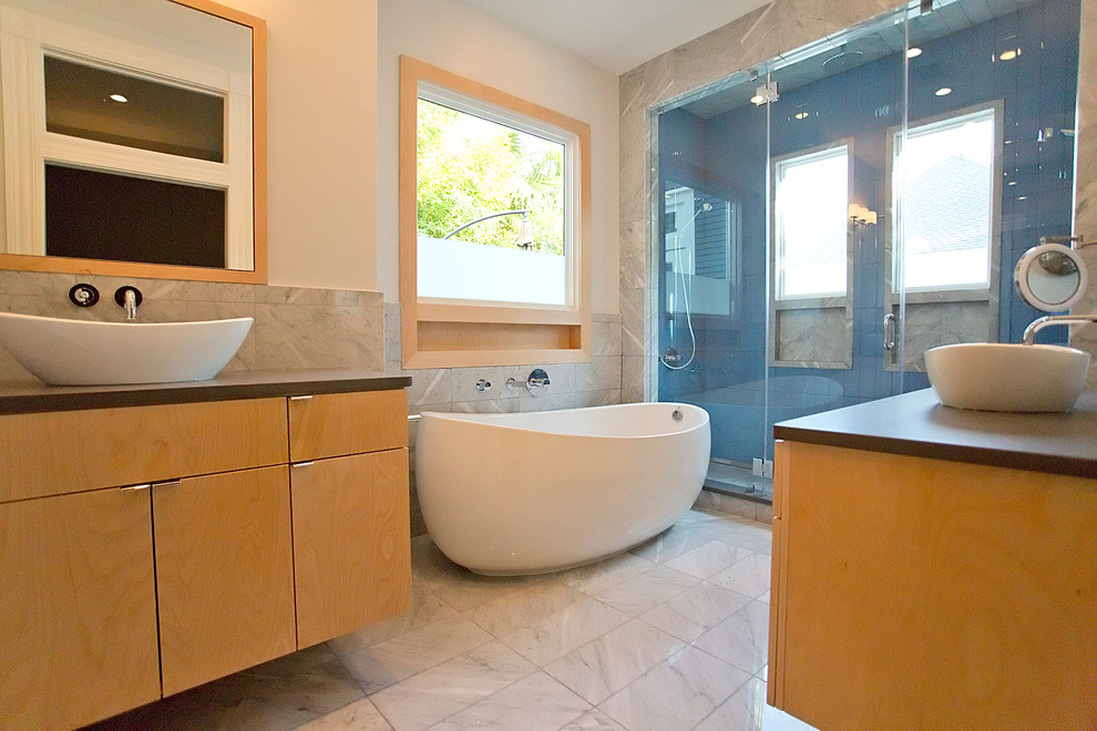 Cette image montre une salle de bain principale design en bois clair de taille moyenne avec une vasque, un placard à porte plane, un plan de toilette en granite, une baignoire indépendante, une douche double, WC séparés, un carrelage blanc, un carrelage en pâte de verre, un mur blanc et un sol en marbre.