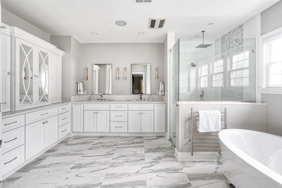 Photo of an expansive traditional ensuite bathroom in New York with shaker cabinets, white cabinets, a freestanding bath, a built-in shower, a bidet, white tiles, porcelain tiles, beige walls, marble flooring, a submerged sink, quartz worktops, a hinged door and white worktops.