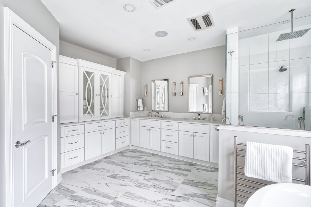 Inredning av ett klassiskt mycket stort vit vitt en-suite badrum, med skåp i shakerstil, vita skåp, ett fristående badkar, en kantlös dusch, en bidé, vit kakel, porslinskakel, beige väggar, marmorgolv, ett undermonterad handfat, bänkskiva i kvartsit och dusch med gångjärnsdörr