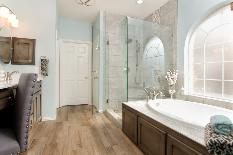 This is an example of a medium sized traditional ensuite bathroom in Dallas with freestanding cabinets, medium wood cabinets, a corner shower, a one-piece toilet, beige tiles, porcelain tiles, blue walls, porcelain flooring, marble worktops, a built-in bath and a submerged sink.