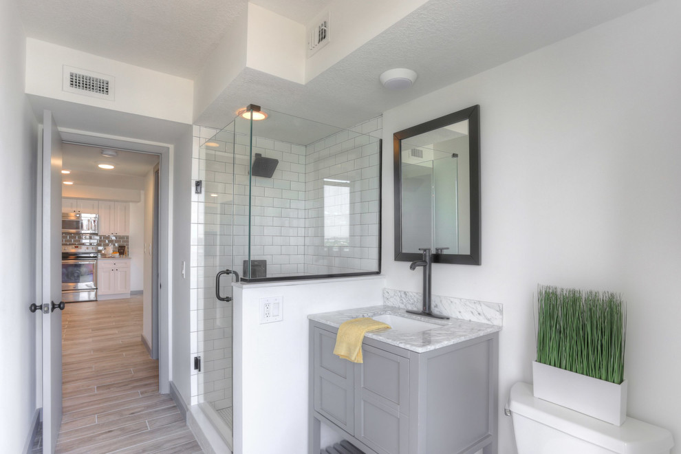 Small traditional shower room bathroom in Tampa with flat-panel cabinets, grey cabinets, a walk-in shower, a two-piece toilet, white tiles, ceramic tiles, white walls, porcelain flooring, a submerged sink and marble worktops.