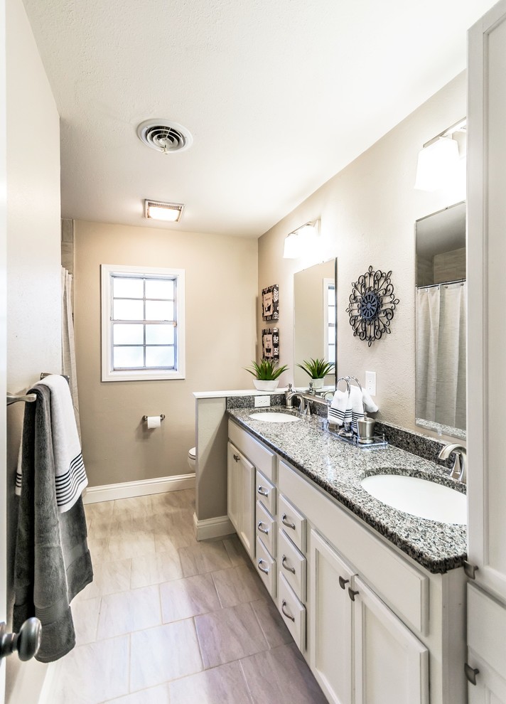 Photo of a traditional bathroom in New Orleans with recessed-panel cabinets, white cabinets, beige tiles, ceramic tiles, beige walls, ceramic flooring and granite worktops.