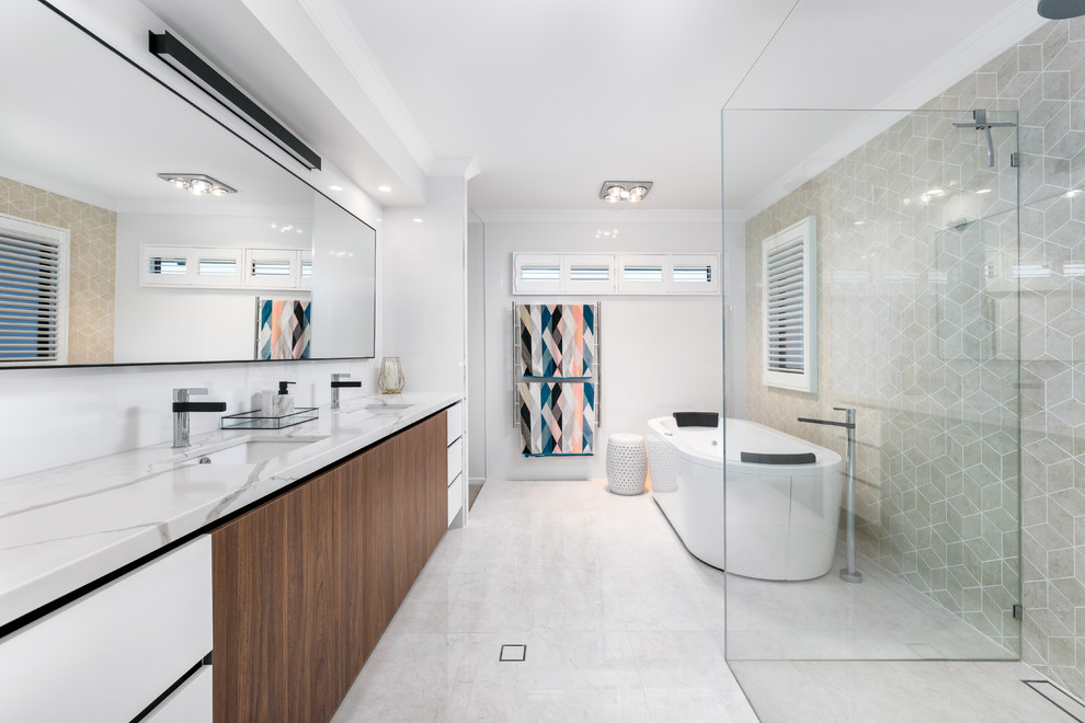 Modernes Badezimmer En Suite mit flächenbündigen Schrankfronten, dunklen Holzschränken, freistehender Badewanne, bodengleicher Dusche, beigen Fliesen, weißer Wandfarbe, Unterbauwaschbecken, weißem Boden und weißer Waschtischplatte in Brisbane