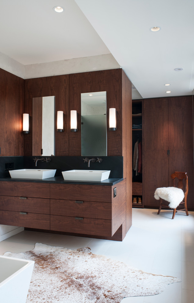 Réalisation d'une salle de bain design en bois foncé avec une vasque et un placard à porte plane.