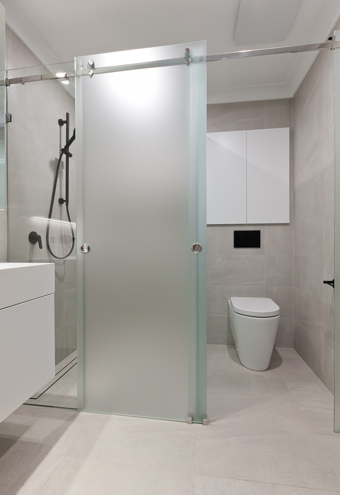 Modern inredning av ett litet vit vitt badrum med dusch, med släta luckor, vita skåp, en toalettstol med separat cisternkåpa, beige kakel, porslinskakel, beige väggar, klinkergolv i porslin, ett integrerad handfat, bänkskiva i akrylsten, beiget golv och dusch med skjutdörr