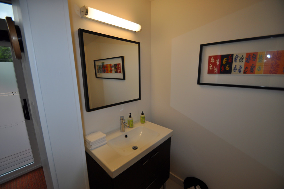 Photo of a contemporary bathroom in Denver with an integrated sink, flat-panel cabinets, dark wood cabinets, a one-piece toilet and white walls.