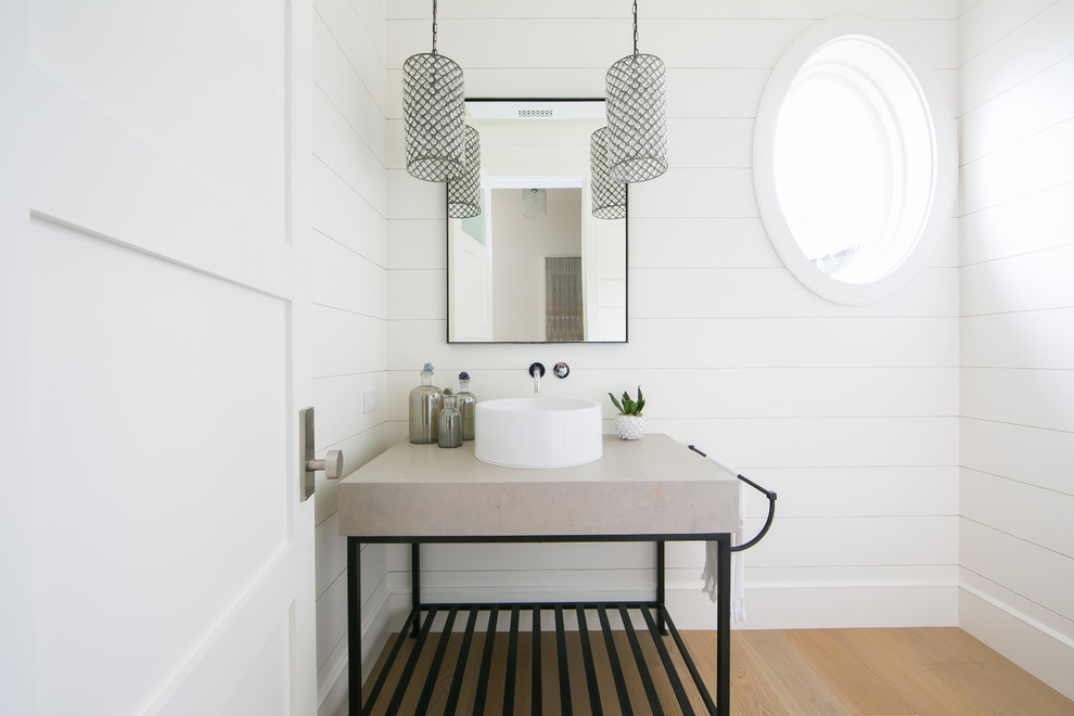 Diseño de cuarto de baño costero con armarios abiertos, paredes blancas, suelo de madera clara, lavabo sobreencimera y suelo marrón