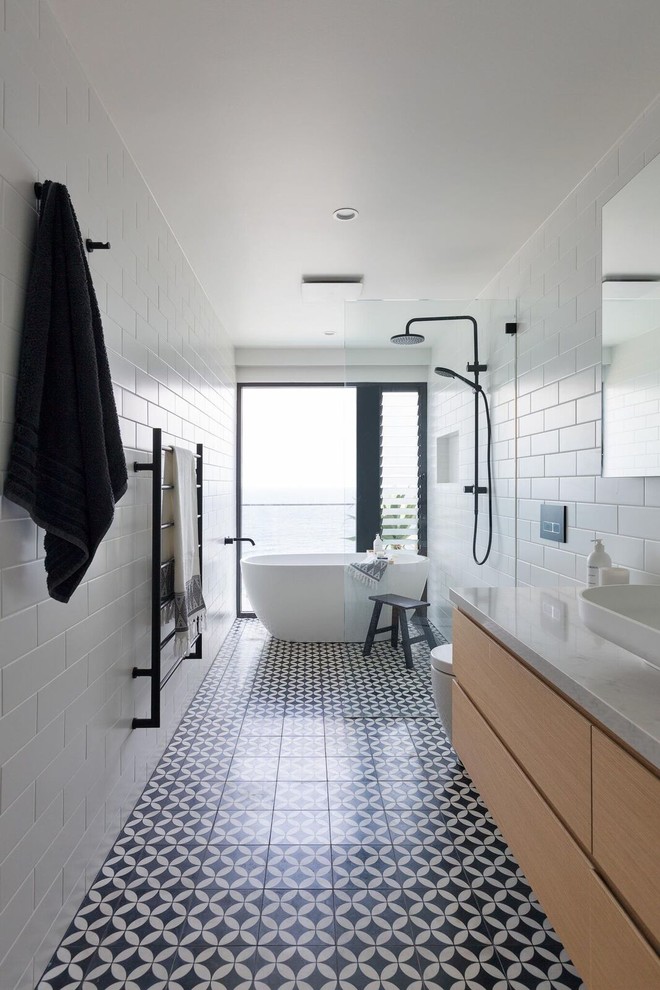 Идея дизайна: главная ванная комната в современном стиле с отдельно стоящей ванной, душевой комнатой, инсталляцией, белой плиткой, плиткой кабанчик, полом из керамической плитки, мраморной столешницей, разноцветным полом, открытым душем, плоскими фасадами, настольной раковиной, светлыми деревянными фасадами и разноцветной столешницей