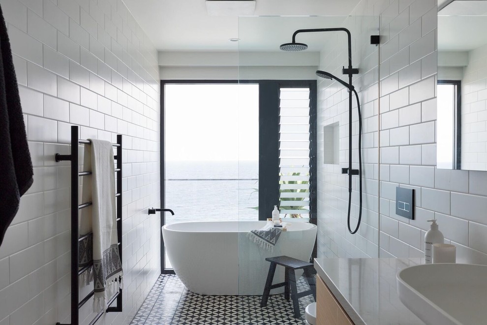 Источник вдохновения для домашнего уюта: главная ванная комната в современном стиле с фасадами островного типа, светлыми деревянными фасадами, отдельно стоящей ванной, душевой комнатой, инсталляцией, белой плиткой, плиткой кабанчик, белыми стенами, полом из керамической плитки, консольной раковиной, мраморной столешницей, разноцветным полом и открытым душем