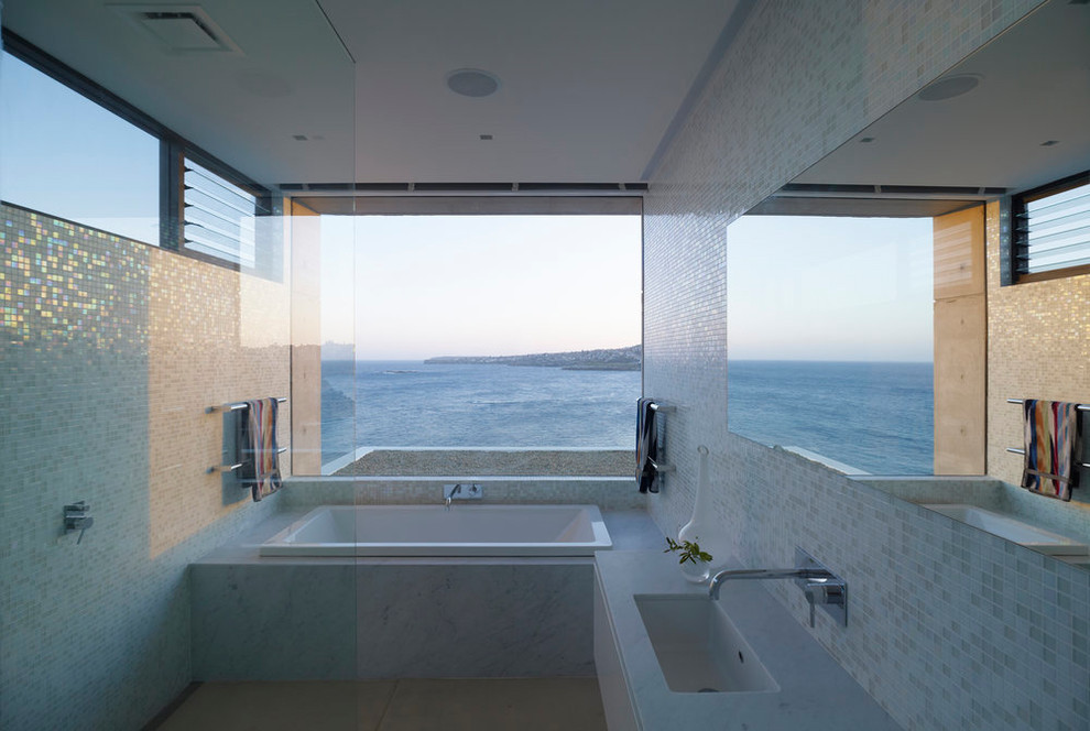 Photo of a large coastal ensuite bathroom in Sydney with a built-in bath, a walk-in shower, beige tiles, ceramic tiles, an integrated sink, marble worktops, a hinged door and white worktops.