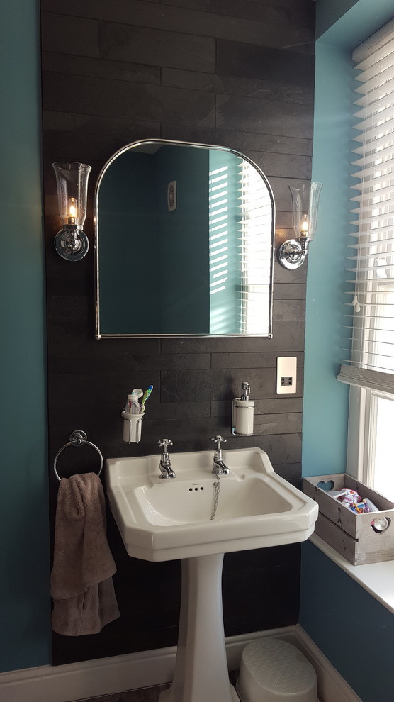Klassisches Badezimmer mit schwarzen Fliesen, blauer Wandfarbe und Sockelwaschbecken in Sonstige