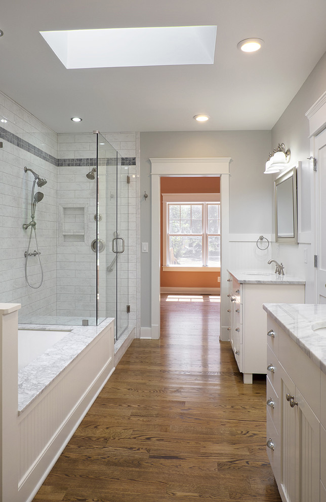 Inspiration for a large timeless master white tile and stone tile medium tone wood floor corner shower remodel in Louisville with an undermount sink, shaker cabinets, white cabinets, marble countertops, an undermount tub and gray walls