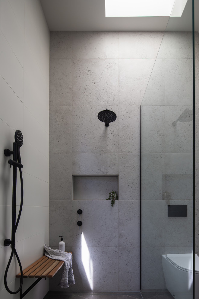 Inredning av ett modernt badrum, med grå kakel och grått golv